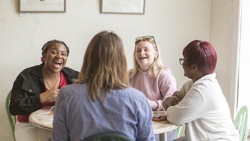 Four students sitting at a coffee table laughing together