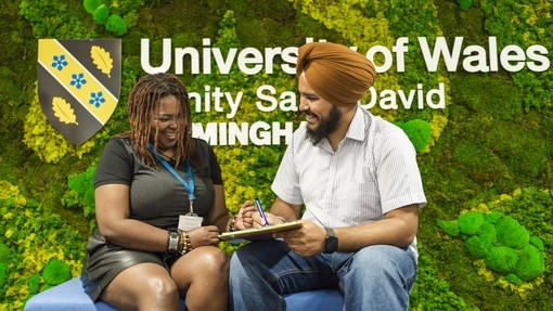 Students in front of green wall with UWN logo