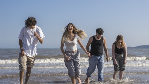 four students on beach playing in shallow water