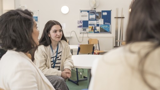 student around a table with other students inside London campus