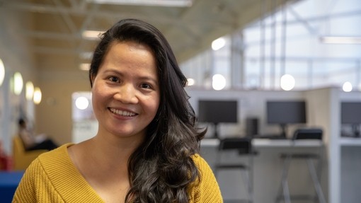 Student wearing a yellow shirt smiling at the camera