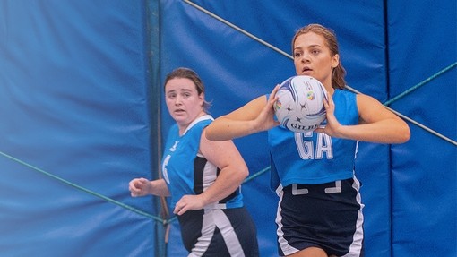 Two netball players with one holding the ball
