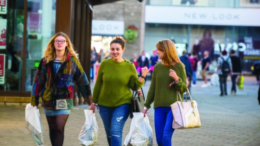 three students walking with shopping bags